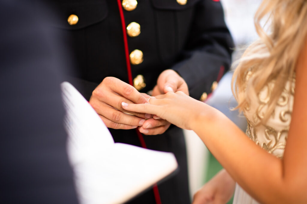 Photo of a man in dress uniform putting a ring on his bride's finger